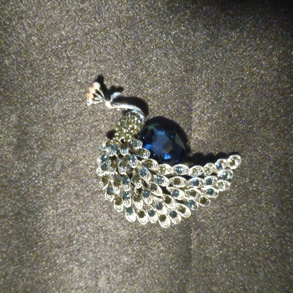 Beautiful flashy silver tone peacock brooch with a large dark blue crystal